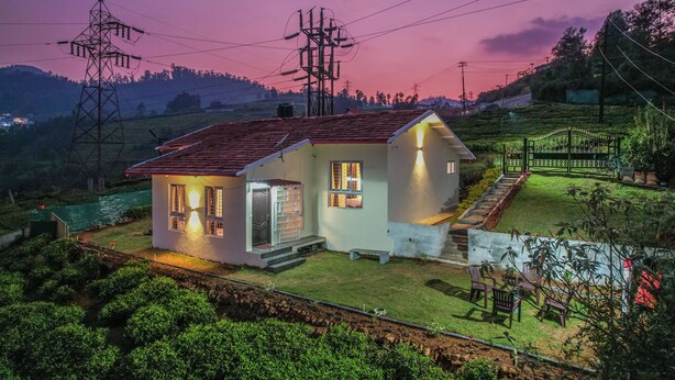 A house with a red roof, a small porch, and a well-lit front door. - The springs Nilgiris (Kotagiri)