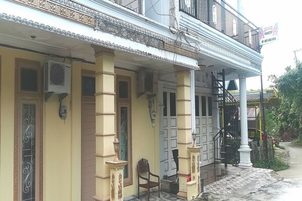 A traditional building with a balcony, decorative columns, and a staircase leading to the upper floor. - OYO 94078 Azzahra Homestay Syariah  (Samarinda)