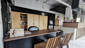 Una recepción con mostrador de madera, sillas negras y una pared oscura con ventanal.