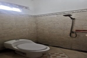 A small bathroom with a toilet, a shower, and tiled walls. - OYO 94078 Azzahra Homestay Syariah  (Samarinda)