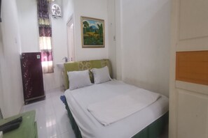 A bedroom with a bed, a green chair, a wardrobe, a painting, and a window with curtains. - OYO 94078 Azzahra Homestay Syariah  (Samarinda)