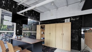 Una cocina moderna con encimera negra, armarios de madera y un comedor con sillas de mimbre.