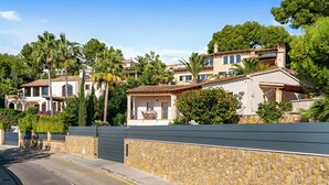 A residential area with multiple houses, a stone wall, and a clear sky. - Luxury 4 bed Villa with private pool Bendinat (Palma de Mallorca)