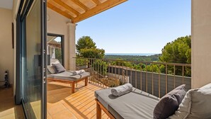 A balcony with two wooden beds and a glass door leading to a room. - Luxury 4 bed Villa with private pool Bendinat (Palma de Mallorca)