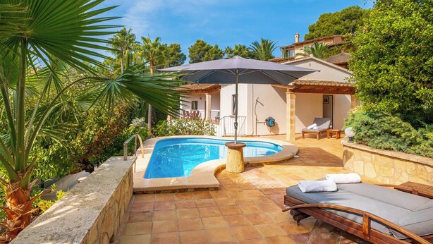A private pool area with a sun umbrella, lounge chairs, and a stone wall. - Luxury 4 bed Villa with private pool Bendinat (Palma de Mallorca)
