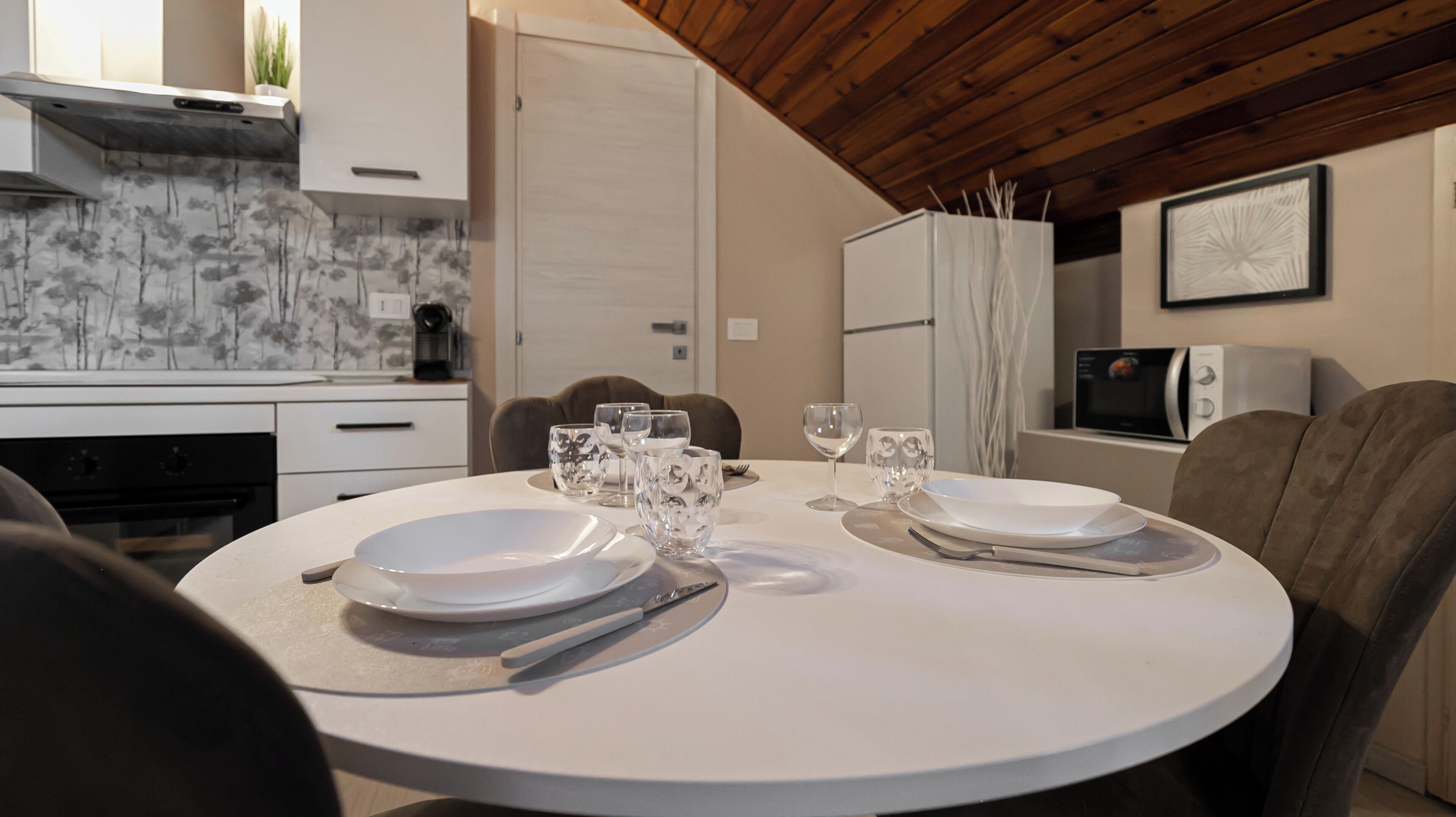 A dining area with a round table set for two, equipped with plates, glasses, and cutlery.