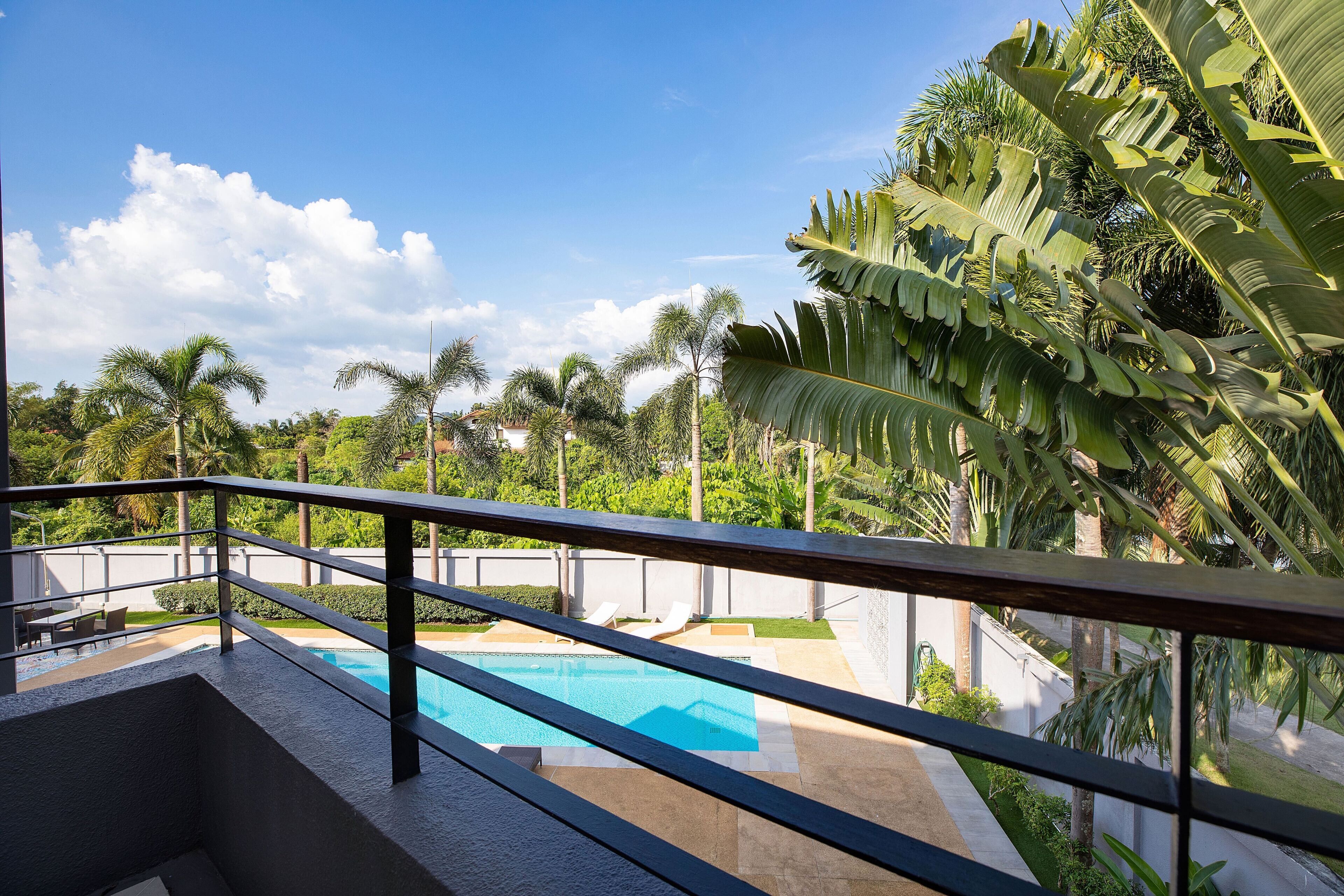 A poolside view with a clear blue sky, palm trees, and a modern pool area.