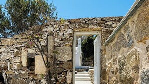 A stone building with a rustic entrance, a large terracotta pot, and a clear sky. - Stone Built Villa Ferretti #Unoblu (Mykonos)
