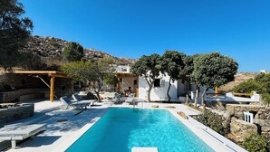 A pool with lounge chairs and a no-entry sign, surrounded by white buildings and trees. - Stone Built Villa Ferretti #Unoblu (Mykonos)