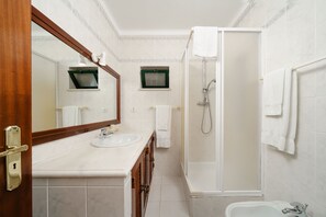 Ein Badezimmer mit Holztür, Waschbecken, Spiegel, Dusche und Badewanne.