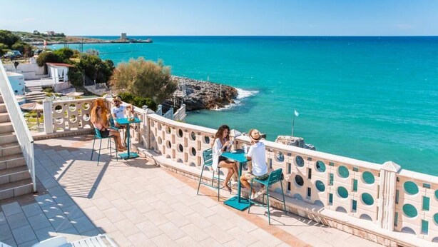 A terrace with outdoor seating overlooking a coastal area. - sfinal residence (Peschici)
