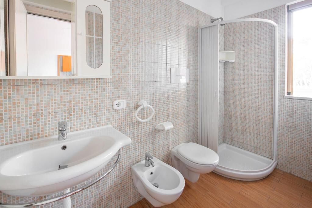 A bathroom with a sink, bidet, toilet, and a shower area.