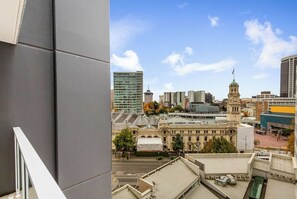 A cityscape with modern and historic buildings, a prominent clock tower, and a clear sky. - Stylish Modern Unit w/ Balcony & Pool by Zodiak (Auckland)