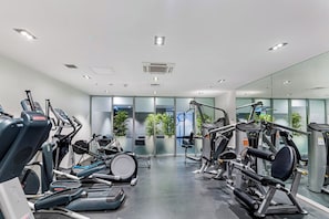 A gym with various exercise equipment, including treadmills, stationary bikes, and weight machines. - Stylish Modern Unit w/ Balcony & Pool by Zodiak (Auckland)