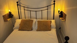 Un letto con struttura in metallo, due cuscini e due lampade fissate alla parete.