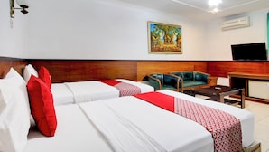 Une chambre d’hôtel avec deux lits, une télévision, un tableau et une tête de lit en bois.