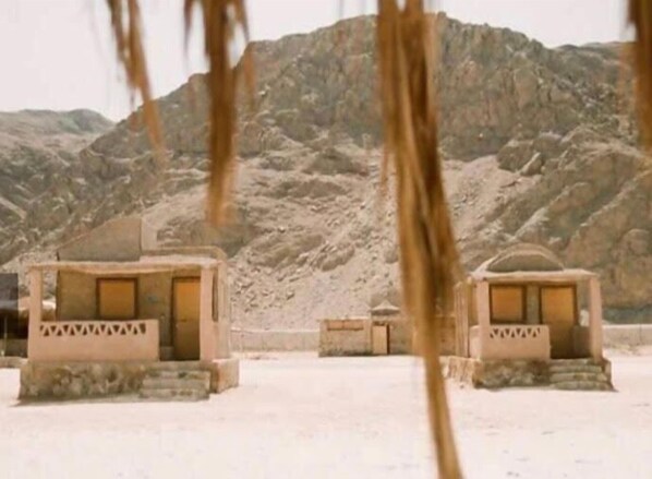 A desert landscape with a few small, isolated buildings with flat roofs and simple architecture. - Aqua Sun (Nuweiba)