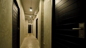 A narrow hallway with a concrete floor and walls, leading to a door at the end.