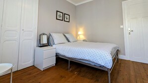 A bedroom with a bed, a nightstand, a dresser, and two doors.