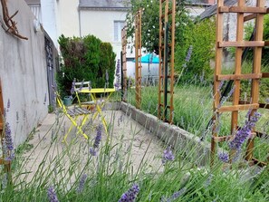 A garden area with a concrete pathway, a wooden ladder, and a yellow chair.