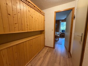 A hallway with wooden paneling and a door leading to a dining area with a table and chairs.