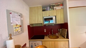 A compact kitchen with a microwave, sink, and wooden cabinets. - Châtel: 2-Room Apartment, Balcony, Parking, WIFI, Pets OK (Châtel)