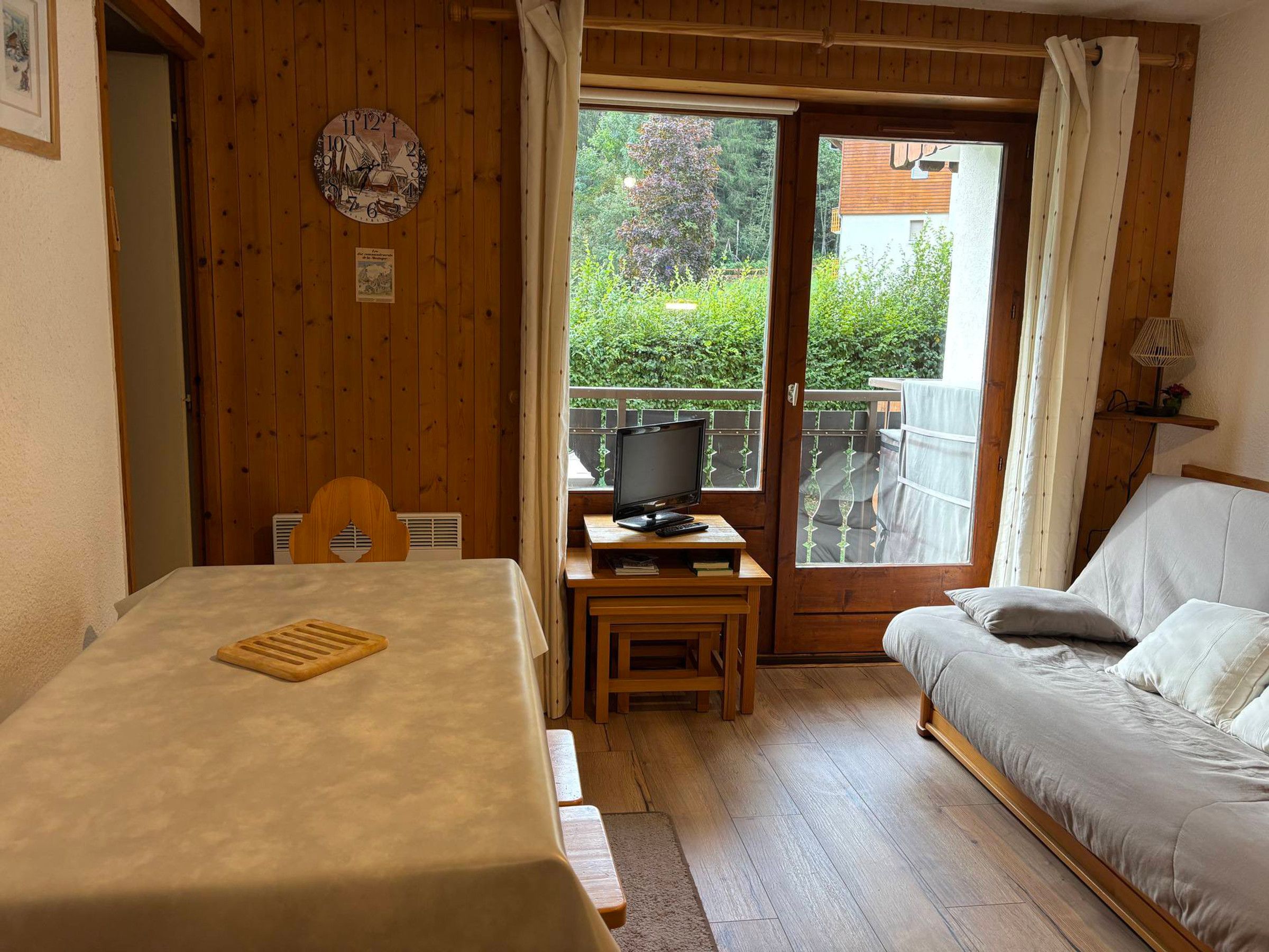 Een kamer met een bed, een tafel met een dienblad, een televisie op een bijzettafeltje en een raam met uitzicht op groen.