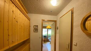 A narrow hallway with wooden paneling on the left, a door on the right, and a small rug on the floor. - Châtel: 2-Room Apartment, Balcony, Parking, WIFI, Pets OK (Châtel)