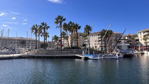 A marina with several boats docked, surrounded by palm trees and buildings.