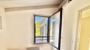 Une chambre avec une grande fenêtre, un lit et une porte.