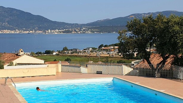 Une piscine offrant une vue sur une ville côtière et sur des montagnes en arrière-plan.