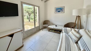 Un salon comprenant un canapé, deux fauteuils, une table, un téléviseur et un lampadaire.