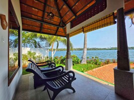 Un espacio cubierto con bancos, vista a un lago y palmeras.