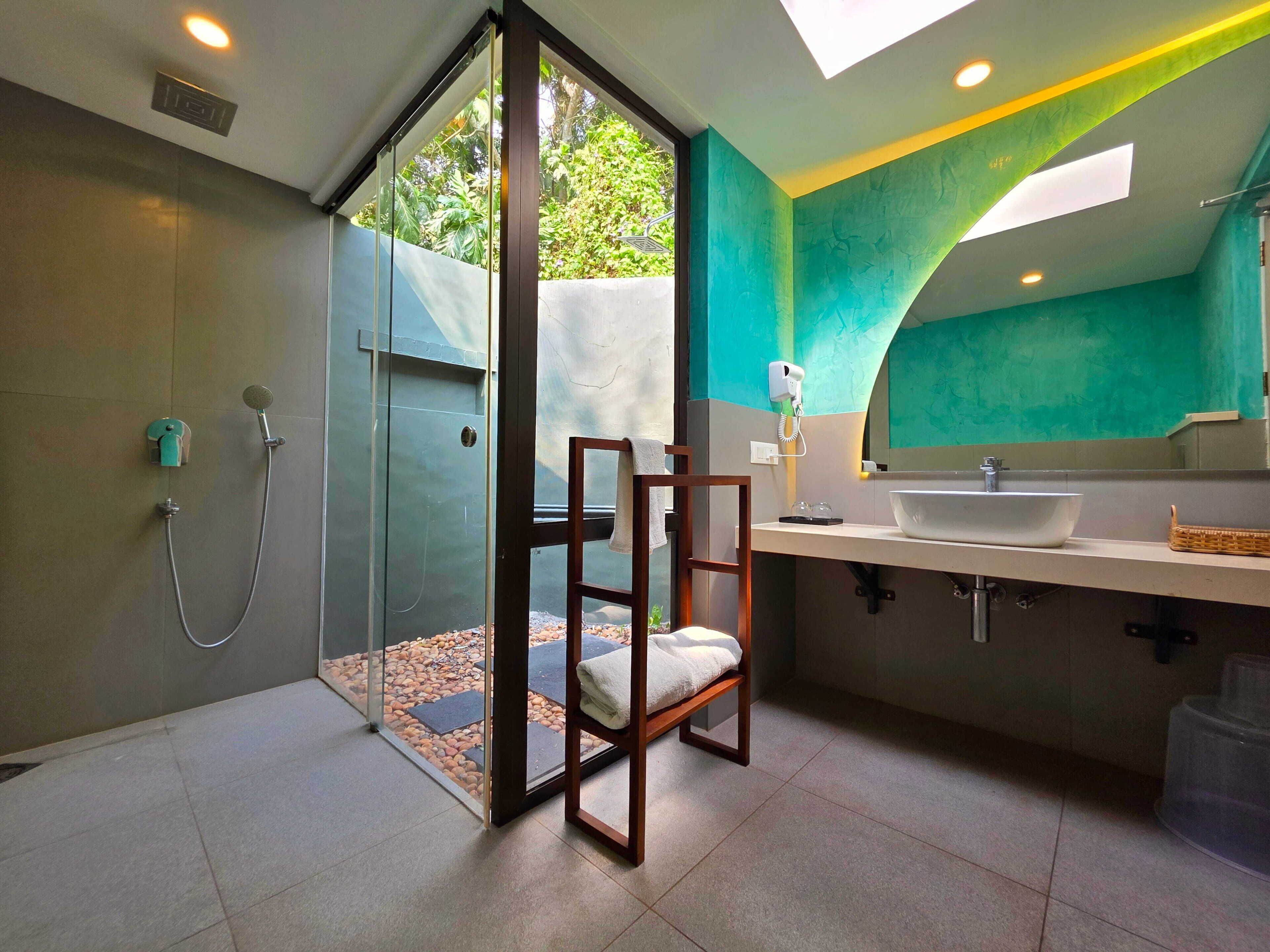 A modern bathroom with a glass shower enclosure, a wooden chair, a sink with a basin, and a large mirror.