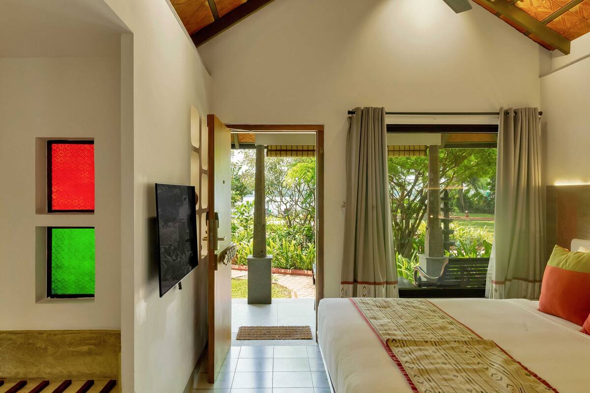 Ein Schlafzimmer mit Bett, Fernseher und Blick auf einen Garten.