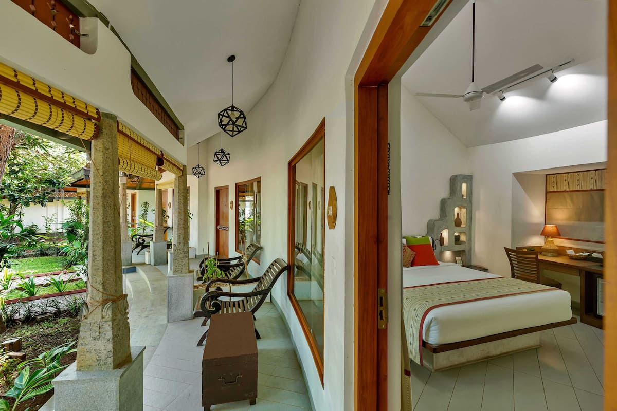 Ein Hotelzimmer mit Bett, Schreibtisch, Stuhl und Blick auf einen Garten.