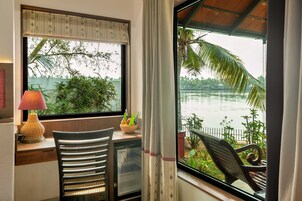 Habitación con vista al agua, un escritorio con lámpara, una silla y un refrigerador pequeño.