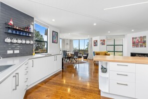 A modern kitchen with white cabinets, a wooden countertop, and a dining area with a table and chairs.