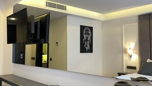 A modern hotel room with a large mirror, a flat-screen TV, a coffee maker, and a bedside table. - PİER HOUSE KAŞ (Kas)