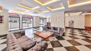 A lobby with a checkered floor, a sofa, a coffee table, and a reception desk. - PİER HOUSE KAŞ (Kas)