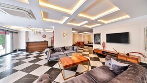 A modern hotel lobby with a checkered floor, a large sofa, a wooden coffee table, and a reception desk. - PİER HOUSE KAŞ (Kas)