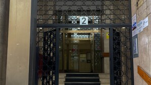 A building entrance with a number '2' sign, a staircase leading up, and a security camera above.