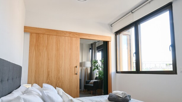 A modern hotel room with a large bed, a wooden wardrobe, and a window with a view.