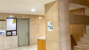 A modern interior with a sign for 'Apartamentos' indicating apartment availability. A reception desk is visible with a sign above it.