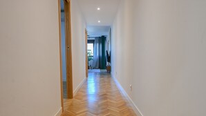 A hallway with wooden flooring and white walls.