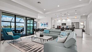 A spacious living area with a large sofa, a teal armchair, and a coffee table. - Intervillas Florida - Villa Majadama (Cape Coral)