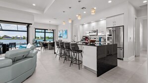 A modern kitchen with a central island, bar stools, and stainless steel appliances. - Intervillas Florida - Villa Majadama (Cape Coral)