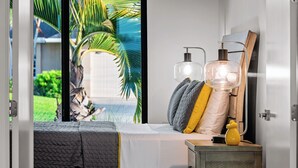 A bedroom with a bed, bedside table, and a view of a garden. - Intervillas Florida - Villa Majadama (Cape Coral)