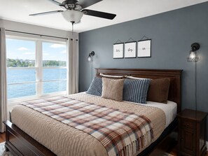 A bedroom with a large bed, a ceiling fan, a view of the water, and framed artwork on the wall. - Waters Ledge-Amazing Lakeview, Deck, Pools , Beach (Osage Beach)