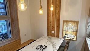 A dining area with a marble table, wooden chairs, a rope chandelier, and a view of the outside through a window. - Le Refuge des Skieurs (Mont-Dore)